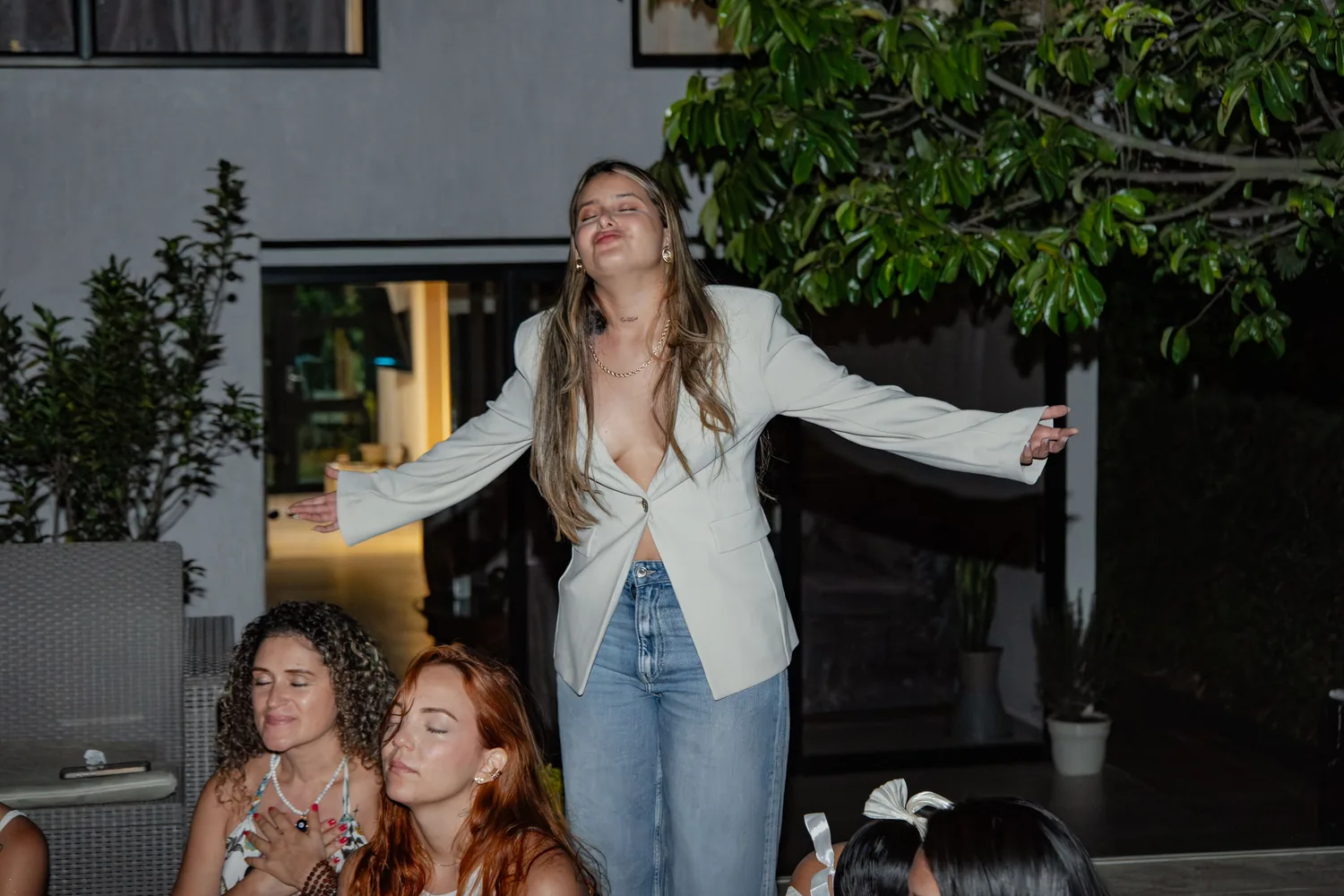Brielah con los brazos abiertos y los ojos cerrados junto a un grupo de mujeres en un encuentro
