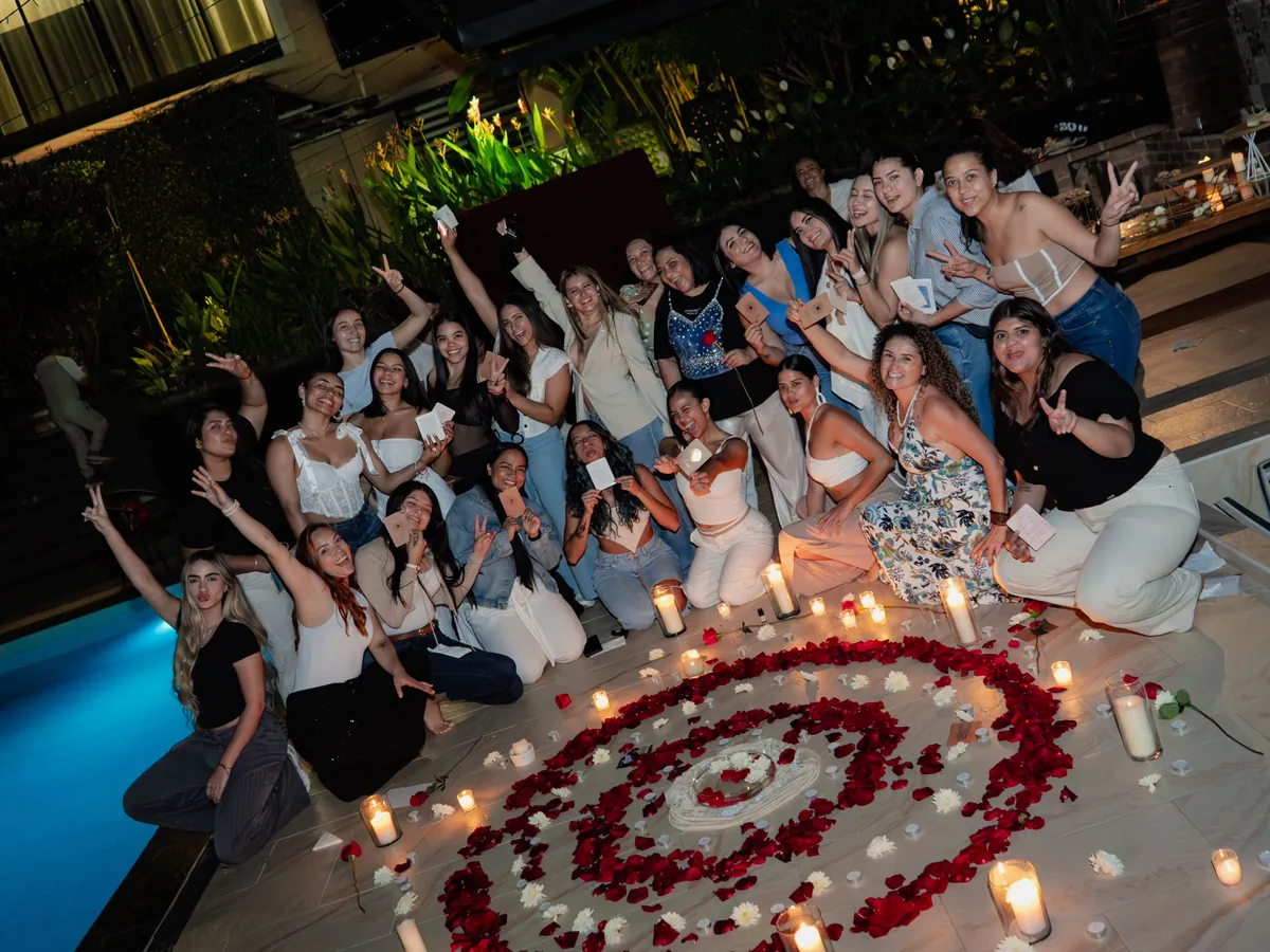 El grupo de mujeres celebra con los brazos en alto junto a velas y pétalos